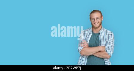 Lächelnde, selbstbewusste Menschen mit gekreuzten Armen blicken auf die Kamera, die auf blauem Hintergrund isoliert ist. Stockfoto