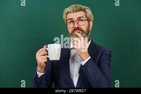 Angenehmer Schluck. Kaffeepause und Entspannung. Mittagszeit für Lehrer. Koffeindosis. Optimistisches Konzept. Lehrer in der Brille trinken Kaffee Kelkboard Hintergrund. Kaffeesüchtig. Energieaufladung für den ganzen Tag. Stockfoto