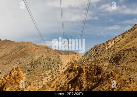 Hochspannungsleitung in Kirgisistan: Elektrizitätspylon in den Bergen. Stockfoto