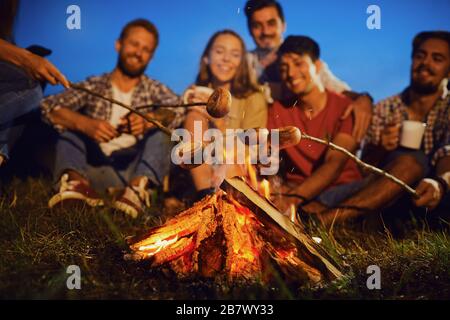 Lagerfeuer in der Nacht auf einem Hintergrund junger lächelnder Menschen bei einem Picknick im Herbst Stockfoto