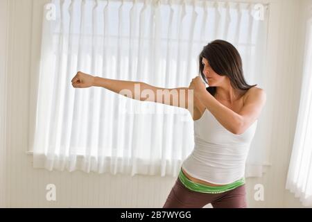 Frau, die eine defensive Haltung hat, während sie in einem Zimmer in ihrem Zuhause steht. Stockfoto