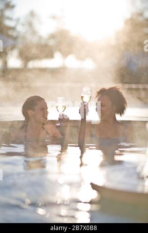 Junge Frauen entspannen im Spa-Pool mit Gläsern Wein Stockfoto