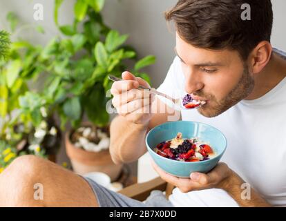 Schöner junger kaukasischer Mann mit Bart und gesundem veganen Frühstück im Freien. Stockfoto