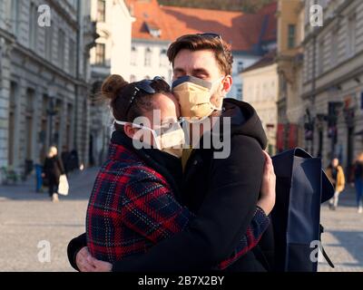 Junge, erschrockene Paare, die sich in der Innenstadt mit einer Gesichtsschutzmaske umarmen, seit das neue Coronavirus Sars-CoV-2 (Covid 19) aufgetaucht ist. Stockfoto
