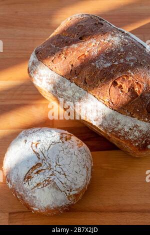 2 Brote frisch gebackenes, hausgemachtes Brot auf einem Holzhackbrett Stockfoto