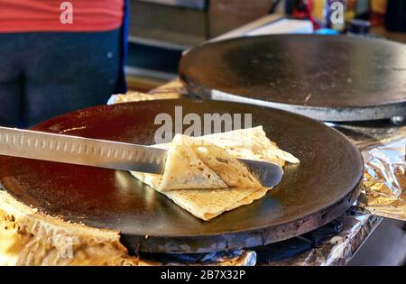 Crepes Pfannkuchen auf einem Markt machen. Ein Crepes wird hochgeklappt. Stockfoto