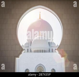 Schöner Blick durch einen weißen Marmorbogen in der Scheich Zayed Moschee in Abu Dhabi, Vereinigte Arabische Emirate. Sonniger Tag Stockfoto