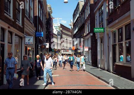 Blick auf die Leute, die auf der Warmoesstraat Straße in Amsterdam spazieren gehen. Es ist eine der ältesten Straßen mit vielen Cafés, Restaurants und Geschäften. Es ist eine sonnige Summe Stockfoto