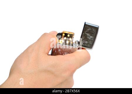Man Hand hält einen Benzinfeuerzeug in der Hand und schlägt dabei einen Feuerstein auf Stockfoto