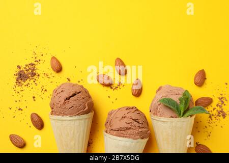 Eiscreme in Kegeln und Mandel auf gelbem Hintergrund. Süßes Essen Stockfoto