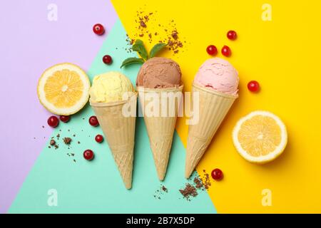 Eis in Konen, Zitrone und Preiselbeere auf mehrfarbigem Hintergrund. Süßes Essen Stockfoto