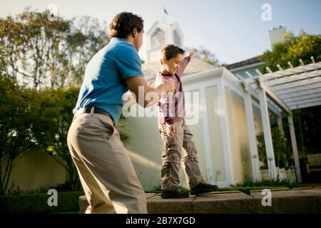 Gerne Mitte der erwachsene Mann helfen, seinen Sohn auf eine Steinmauer zu balancieren. Stockfoto