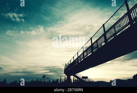 Die Silhouette einer Fußgängerbrücke, die die Straße überquert Stockfoto