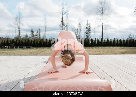Junges Mädchen, das Yoga draußen in ihrem Hinterhof zu Hause macht Stockfoto