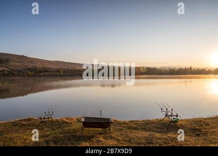 Karpfen angeln karpfen beißen Indikatoren und Rollen auf rod pod in der Nähe des Flusses. Angeln bei Sonnenaufgang. Stockfoto