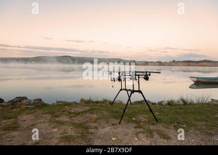 Karpfen angeln karpfen beißen Indikatoren und Rollen auf rod pod in der Nähe des Flusses. Angeln bei Sonnenaufgang. Stockfoto