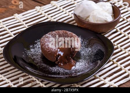 Konzept: Speisekarten, gesundes Essen, hausgemachte, Feinschmecker, Völlerei. Weißen Teller mit Schokolade Fondant und Eis auf einem chaotisch Vintage Holz b Stockfoto