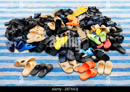 Schuhhaufen, die in verschiedenen Farbkombinationen verkauft werden, ländlicher Landmarkt, Sandalen, lockere Schuhe, alt. Stockfoto