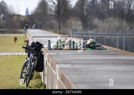 Das öffentliche Leben in Zeiten der Corona-Pandemie am 18. März 2020 im Riemer Park in München. Das frühlingshafte Wetter treibt die Menschen in die frische Luft, an einer Wand liegt ein junges Paar nebeneinander auf dem Rücken und sonnt sich, sie lassen ihre Fahrräder neben sich parken. Sonnen,? SVEN SIMON Fotoagentur GmbH & Co. Pressefoto KG # Prinzess-Luise-Str. 41 # 45479 M uelheim/R uhr # Tel 0208/9413250 # Fax. 0208/9413260 # GLS Bank # BLZ 430 609 67 # Kto. 4030 025 100 # IBAN DE75 4306 0967 4030 0251 00 # BIC GENODEM1GLS # WWW.SVENSIMON.NET. Weltweite Nutzung Credit: Dpa Picture Alliance / Alamy Live News Stockfoto