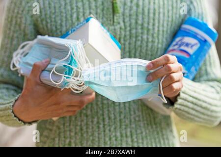 Halten von Gesichtsmasken und Desinfektionswischtüchern zum Schutz vor COVID-19, Coronavirus Infektion Stockfoto