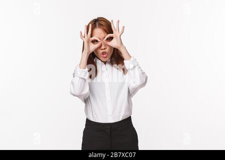 Porträt einer unbeschwerten, lustigen asiatischen Frau, die vor der Arbeit Kawaii-Maske oder Brille mit den Fingern zeigt, als sei sie mit Kindern albern Stockfoto