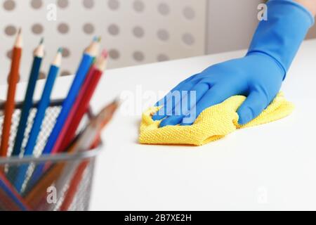 Nahaufnahme der weiblichen Hände in Gummihandschuhen und einem Tuch. Reinigung und Desinfektion des Tischs im Raum. Stockfoto