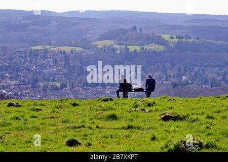 Zwei männliche Rammler, die auf einer Bank sitzen und die Ansicht von Westcott und Leith Hill an einem Frühlingstag von Ranmore Common, Surrey Hills Dorking England UK betrachten Stockfoto