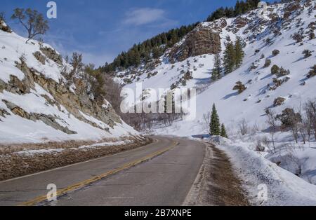 Winter Mountain Drive in Utah: Eine zweispurige Umfahrungskurve zwischen schneebedeckten Hügeln im Nordosten Utahs. Stockfoto