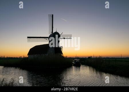 Malerische Aussicht auf die Silhouette einer holländerwindmühle gegen den Dämmerhimmel Stockfoto