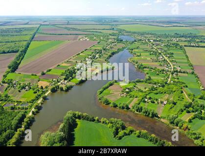 Schöne Landschaft vom Himmel. Der Fluss ist in zwei Bäche aufgeteilt. Viele grüne Felder und Bäume. Vogelperspektive oben. Frühling Natur im Meado Stockfoto