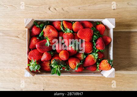 Eine Schachtel mit Erdbeeren, von oben betrachtet, auf einem Holztisch Stockfoto