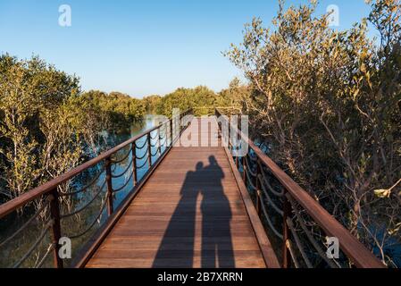 Paar Schatten, während sie den Sonnenuntergang im Mangrove Park in Abu Dhabi, VAE genießen Stockfoto