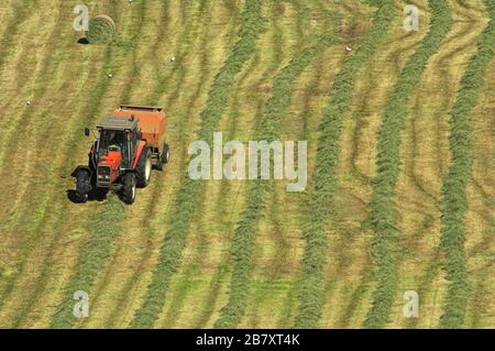 Auf einer Wiese auf einer Bergfarm, Cumbria, Großbritannien, werden große Ballen Silage gemacht. Stockfoto