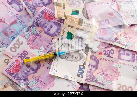 Spritze auf dem Stapel ukrainischer Banknoten. Verkauf von Drogen, Ocain, Heroin oder Ecstasy. Illegales Geschäft. Konzept für das Gesundheitswesen und die Medizin. Stockfoto