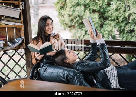 Junge Frauen, die im Pavillon liegen und ein Buch lesen Stockfoto
