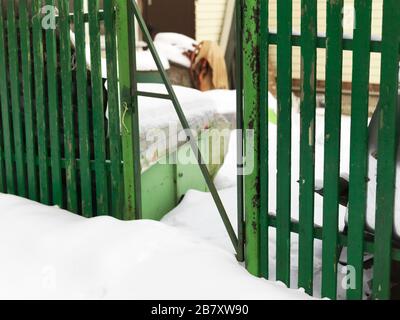 Tür in einem beschädigten Zaun öffnen, Winterszene Stockfoto