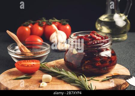 Zum Kochen von sonnengetrockneten Tomaten in einem Glasbecher mit Olivenöl, Knoblauch und Rosmarin. Stockfoto