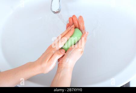 Frau wäscht die Hände mit antibakterieller grüner Seife und Wasser. Hygienekonzept. Coronavirus Schutz Handhygiene antiseptisch. Hautdesinfektionsmittel für Stockfoto
