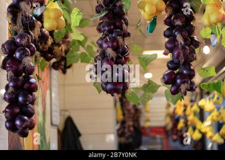 Rote Zwiebeln und Zitronen hängen vor einem Greengrocker. Es gibt einen Markt im Rücken. Nahaufnahme. Stockfoto