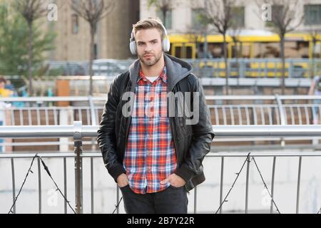 Genießen Sie großartigen Sound. Gutaussehender Kerl hört Tonspur im Freien. Der junge Mann genießt Musik in Ohrhörern. HiFi-Stereo-Sound. Sound- und Musiktechnologie. Modernes Leben. Musikalische Erlebnisse. Stockfoto