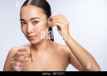 Lächelnde junge Frau, die eine Serumölbehandlung erhält Stockfoto