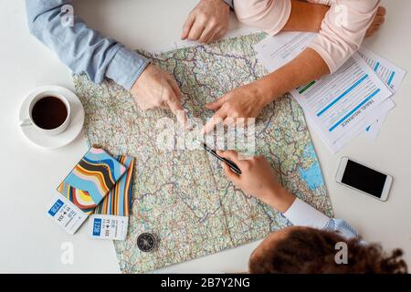 Afrikanische Abstiegsfrau Reisebüro im Büro mit Senioren-Paar Draufsicht Heißkaffee trinken Zielort auf Karte Nahaufnahme wählen Stockfoto