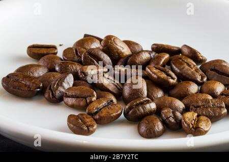 Makroaufnahme von Kaffeebohnen in einer weißen Kaffeetasse Stockfoto