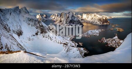 Blick vom Gipfel Reinebringen auf das Dorf Reine und den Fjord im verschneiten Winter, Lofoten Stockfoto