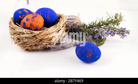 Ein Gelege mit ostereiern und Rosmarin schließt sich auf weißem Grund an Stockfoto
