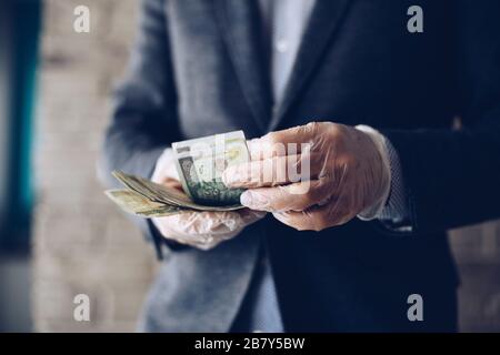 Mann zählt polnische Zloty-Geldscheine in Latex-Schutzhandschuhen. Stockfoto