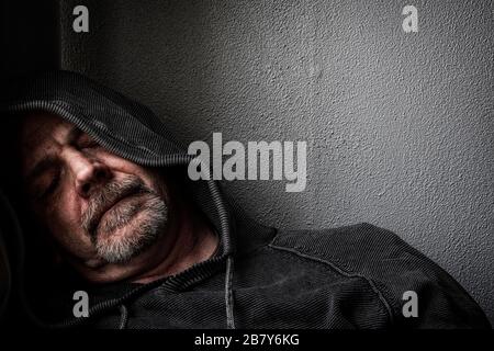 Ein Mann mittleren Alters, der sich in einem ermüdeten Zustand befindet und an Depressionen leidet. Stockfoto