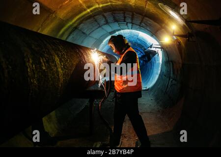 Arbeiter im Schutzmaskenschweißrohr im Tunnel Stockfoto