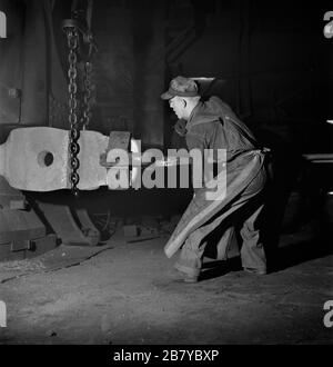 Arbeiter manipulieren ein Heißschmieden, das unter einem Dampfhammer in der Blacksmith Shop von Atchison, Topeka and Santa Fe Railroad, Topeka, Kansas, USA, Jack Delano für US Office of war Information, März 1943 gehämmert wird Stockfoto