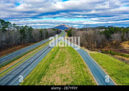 Luftaufnahme einer Straße mit Pilot Mountain in North Carolina, USA und einem wolkenblauen Himmel Stockfoto